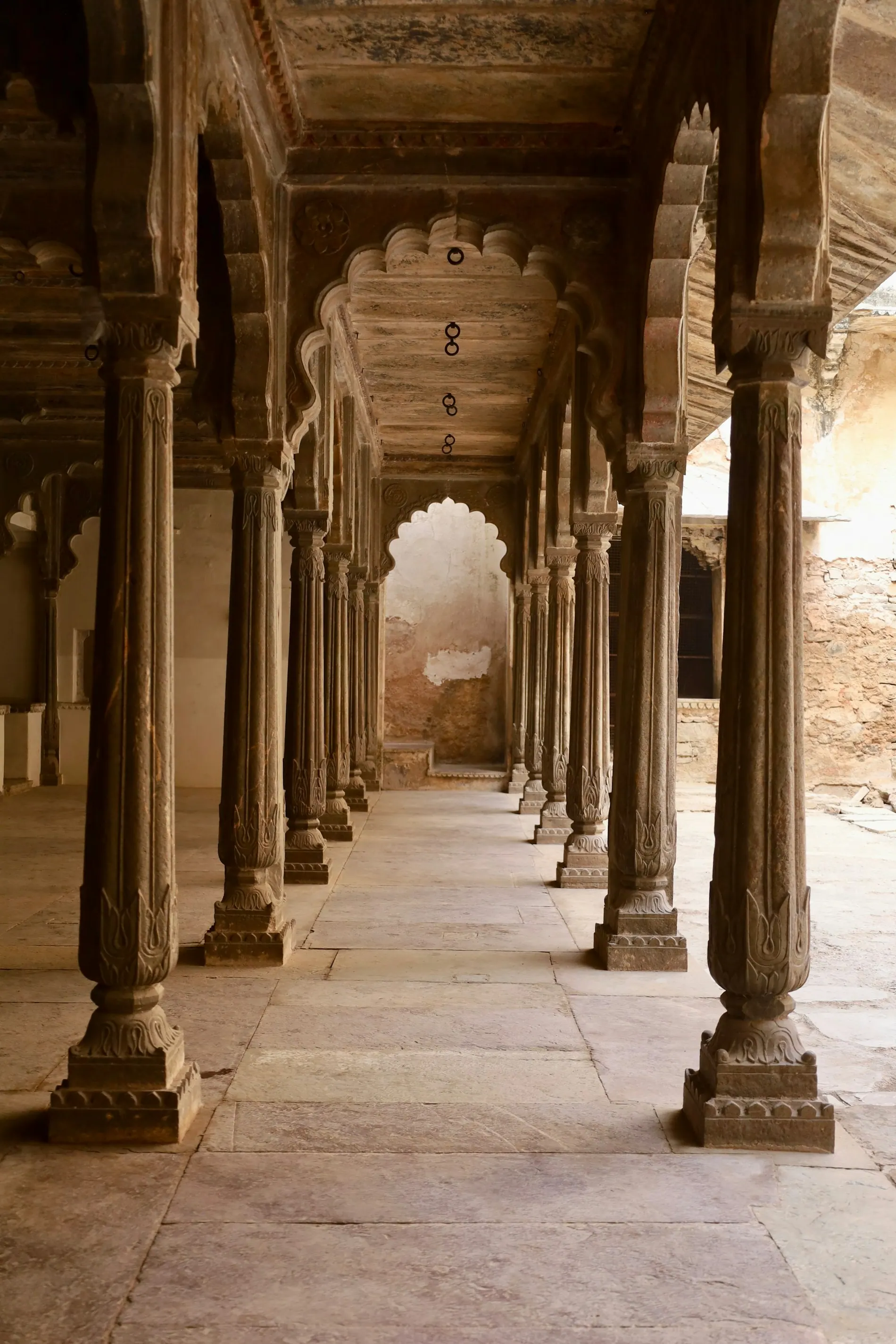 Galerie en pierre aux arches et colonnes, tons chauds et feutrés.